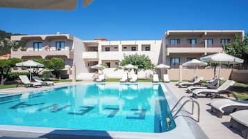 Una piscina al aire libre, sombrillas, sillones reclinables de piscina