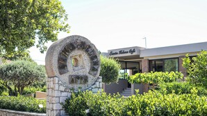 A stone sign with the inscription 'Santo Kalon Cafe' and a modern building with a glass facade in the background. - Santa Helena Hotel Ialysos (Rhodes)