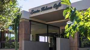 A building with a sign reading 'Santu Akenu Ciyu' and a modern architectural style with glass doors and a staircase leading to the entrance. - Santa Helena Hotel Ialysos (Rhodes)