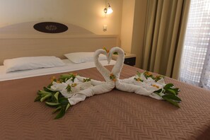 A hotel room with a bed, a wall-mounted light, and a window with curtains. - Santa Helena Hotel Ialysos (Rhodes)