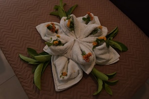 A bed with a brown quilted cover and a towel arrangement in the center. - Santa Helena Hotel Ialysos (Rhodes)