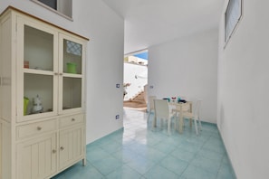 A compact room with a dining area, a cabinet with glass doors, and a view of a staircase leading outside. - Le Dimore Turchesi (Salve)