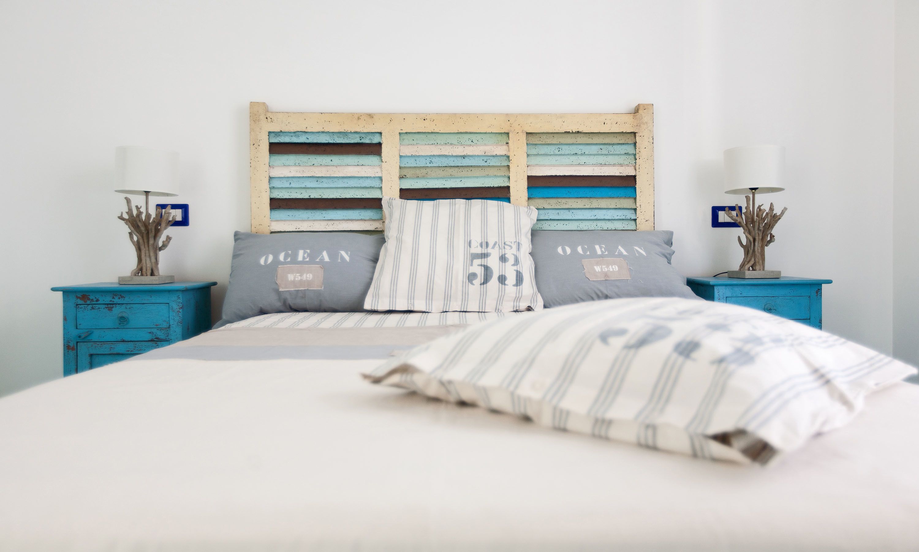 A bed with striped pillows, a wooden headboard, and two nightstands with decorative items.