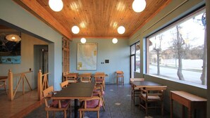 A dining area with wooden tables and chairs, a map on the wall, and large windows with a view of the outside. - Hotel Saltos del Paine (Natales)