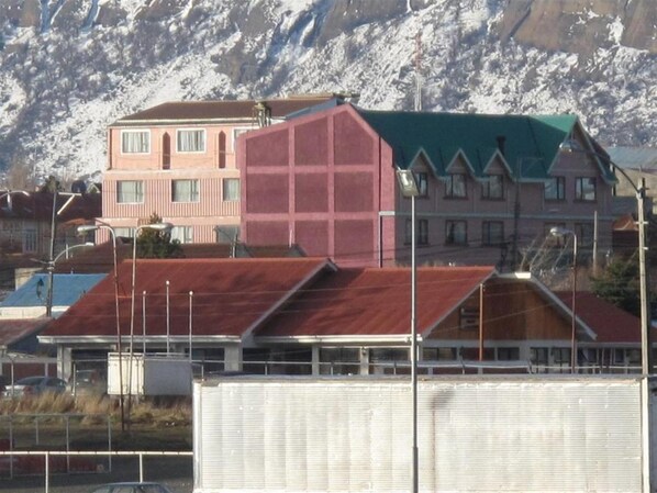 A building with a red roof and a green roof, surrounded by snow-capped mountains.