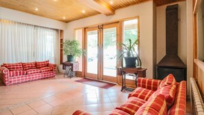 A spacious living area with a red and white checkered sofa, a wooden ceiling, and a fireplace. - Hotel Saltos del Paine (Natales)