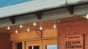 A hotel entrance with double wooden doors, a sign reading "Hotel Salitos del Pinar," and a brick facade. - Hotel Saltos del Paine (Natales)