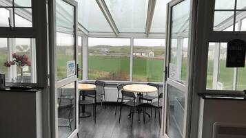 A conservatory with a view of a green field, a table with chairs, and a sign indicating a whiskey brand.