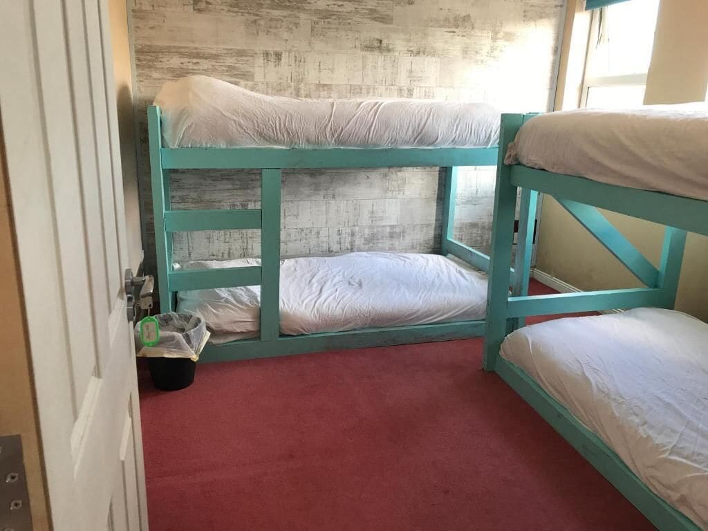 Quarto com beliche, tapete vermelho e parede de madeira.