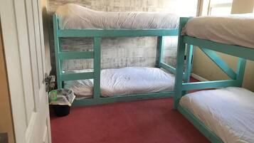 Quarto com beliche, tapete vermelho e parede de madeira.