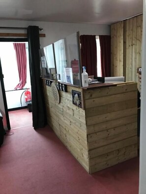 A room with a wooden partition, a mirror, a small table with a bottle, and a red curtain. - Finn McCool's Giants Causeway Hostel (Bushmills)