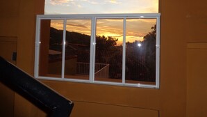 Une fenêtre donnant sur un paysage vallonné, avec une vue sur le coucher du soleil.