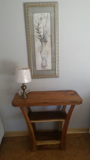 A wooden console table with a lamp and a framed artwork on the wall.