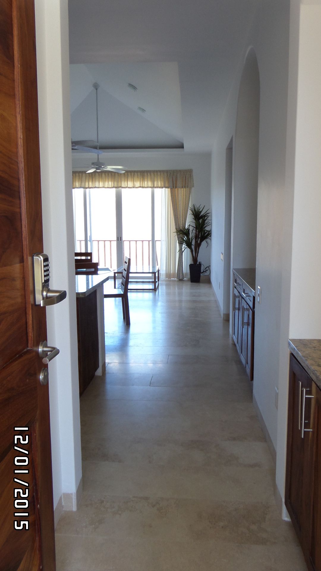 A spacious hallway with a dining area, a ceiling fan, and a potted plant.