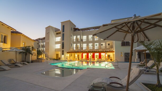 A hotel courtyard with a swimming pool, lounge chairs, and umbrellas.
