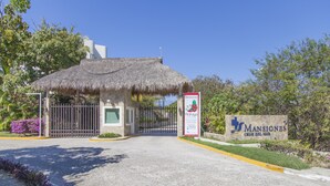 A gated entrance to a property named 'Mansiones' with a thatched-roof structure.