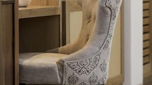 A chair with a tufted backrest and patterned upholstery in a bathroom setting.