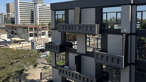 Een modern gebouw met meerdere verdiepingen, grote ramen en een combinatie van baksteen en beton.