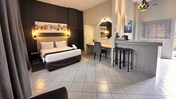 Een moderne hotelkamer met een groot bed, een bureau, een stoel en een kleine bar.