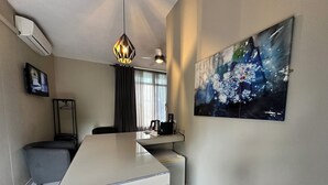 Een moderne hotelkamer met een grote witte eettafel, een schilderij aan de muur en een plafondventilator.