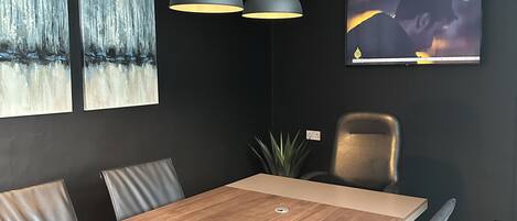 A modern dining area with a wooden table, black walls, and two pendant lights.