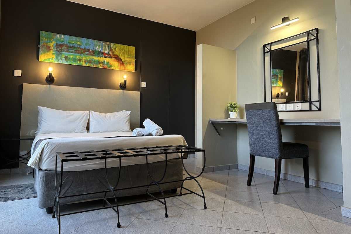 Een moderne hotelkamer met een bed, een bureau, een stoel en een schilderij aan de muur.
