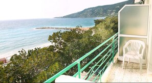 A balcony with a white plastic chair, overlooking a beach and ocean. - Hotel Savoia (Ospedaletti)