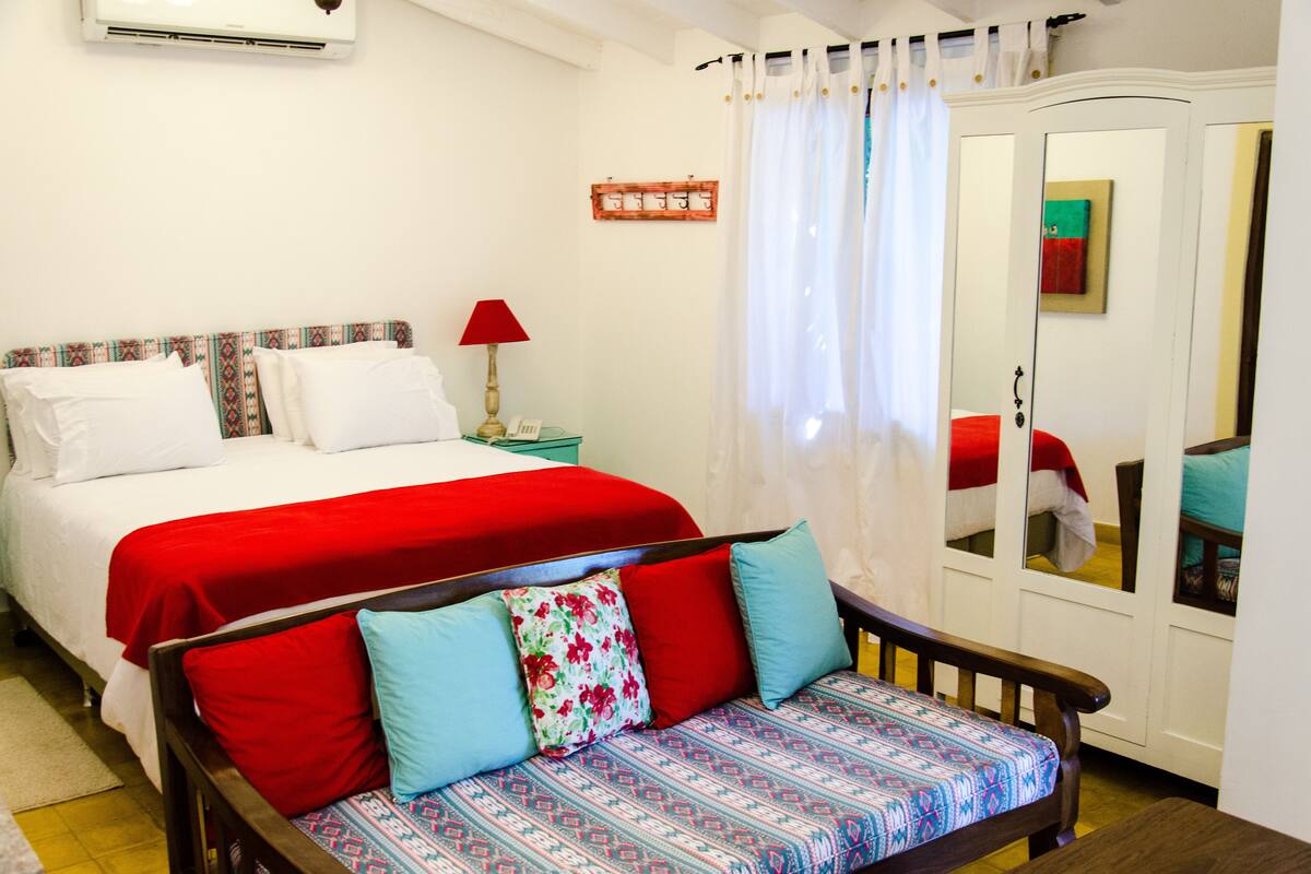 A bedroom with a bed, a bedside table with a lamp, a wardrobe, and a sofa.
