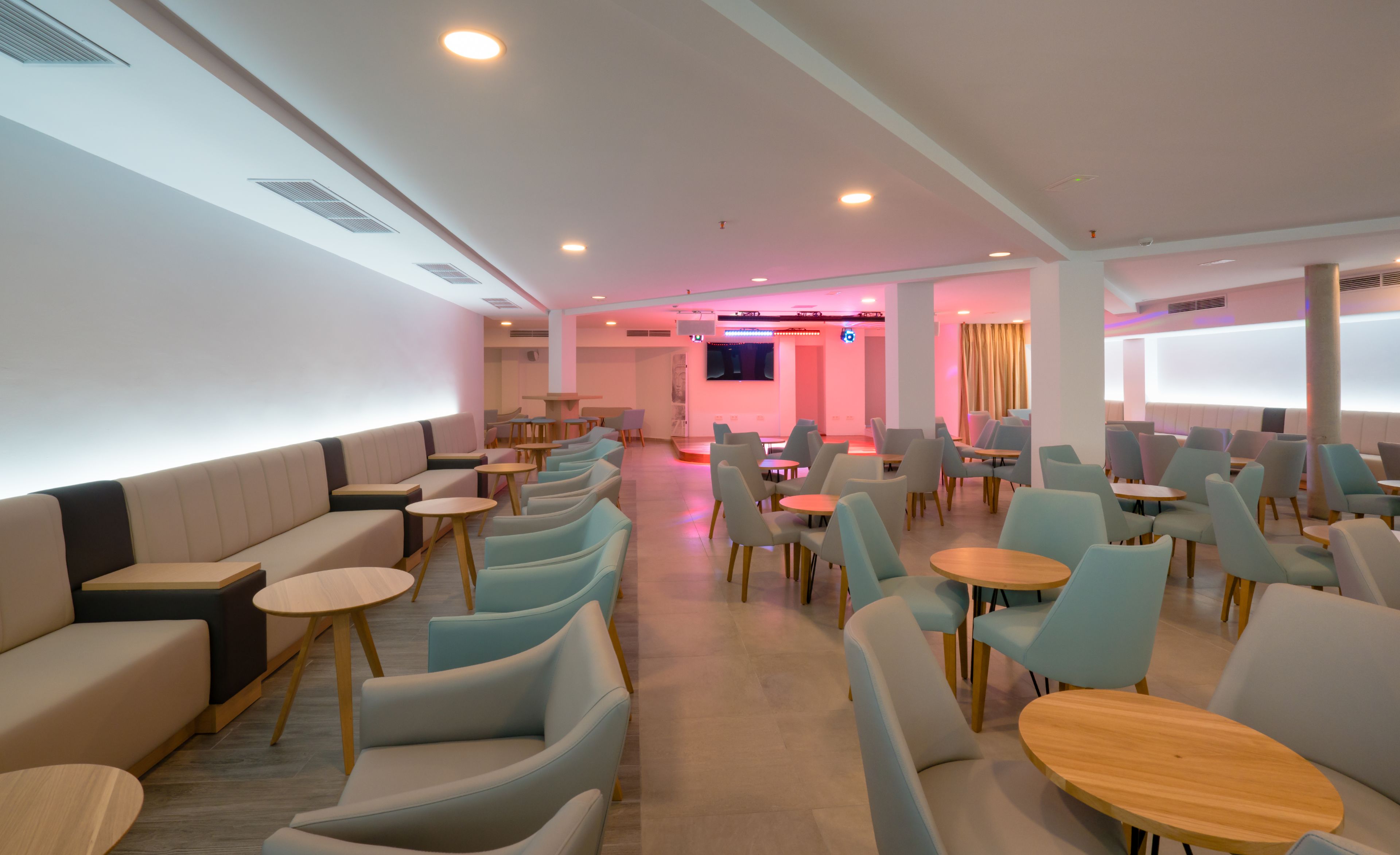 A modern, well-lit lounge area with seating arrangements including sofas and round tables.