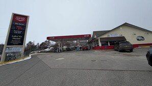 A gas station with a sign indicating services at 17.29, a motel, and a restaurant. - Lake-Vu Motel (Kenora)
