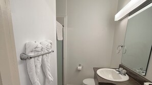 A bathroom with a toilet, sink, towel rack, and a mirror. - Lake-Vu Motel (Kenora)