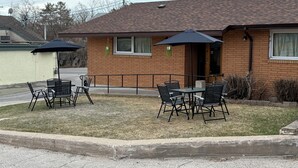 A brick building with outdoor seating and a covered patio area. - Lake-Vu Motel (Kenora)