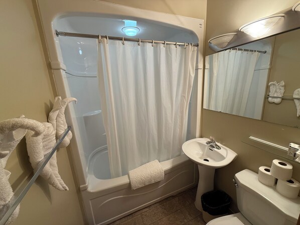 A bathroom with a bathtub, a sink, a toilet, and a mirror.
