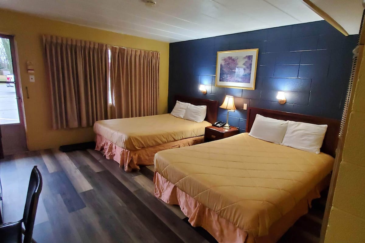 A hotel room with two beds, a desk, and a chair.