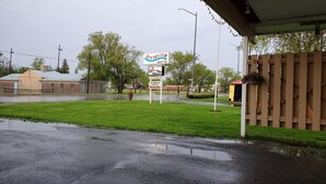 Ein Motel namens Riverview mit einer Rasenfläche, einem Holzzaun und einem Schild, das den Namen und den Standort des Motels angibt.