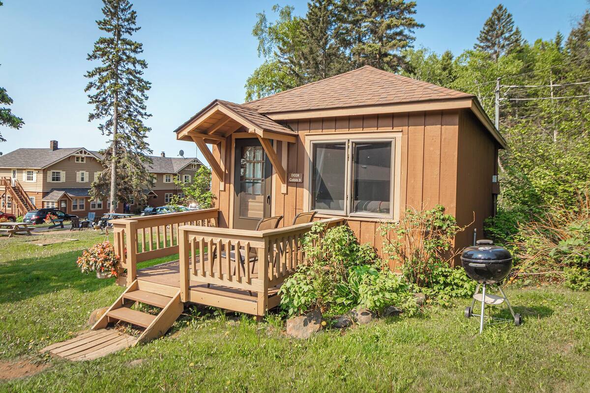 A small cabin with a wooden deck, a front door, and a window.