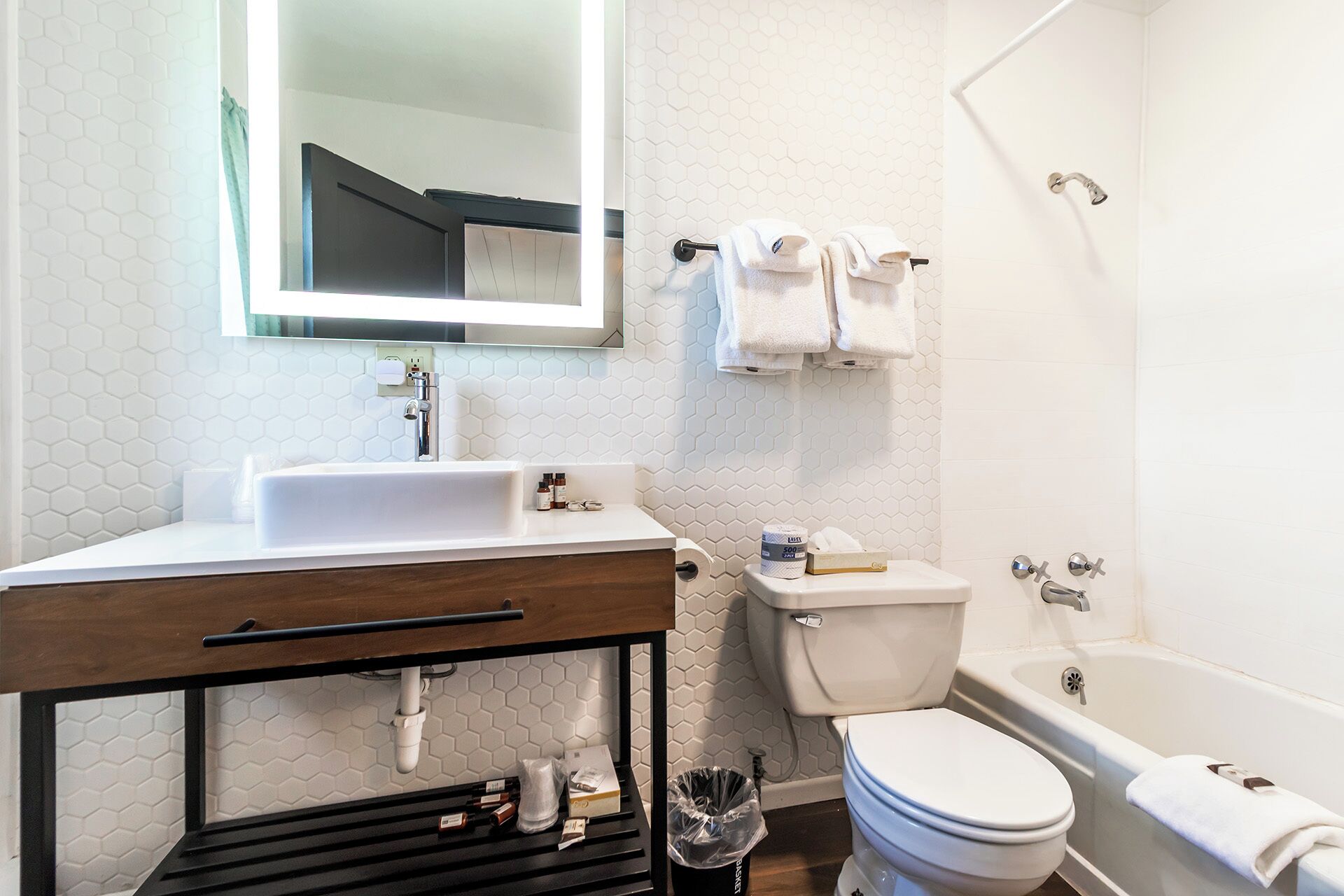 A modern bathroom with a white sink, mirror, toilet, and bathtub.