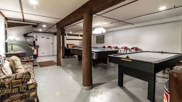 A pool table in a room with a couch and a lamp.