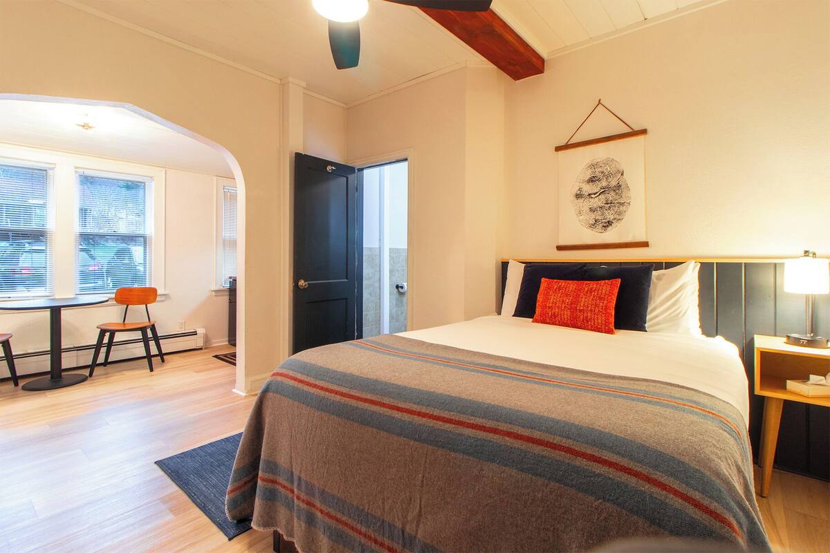 A bedroom with a bed, a desk, and a chair.