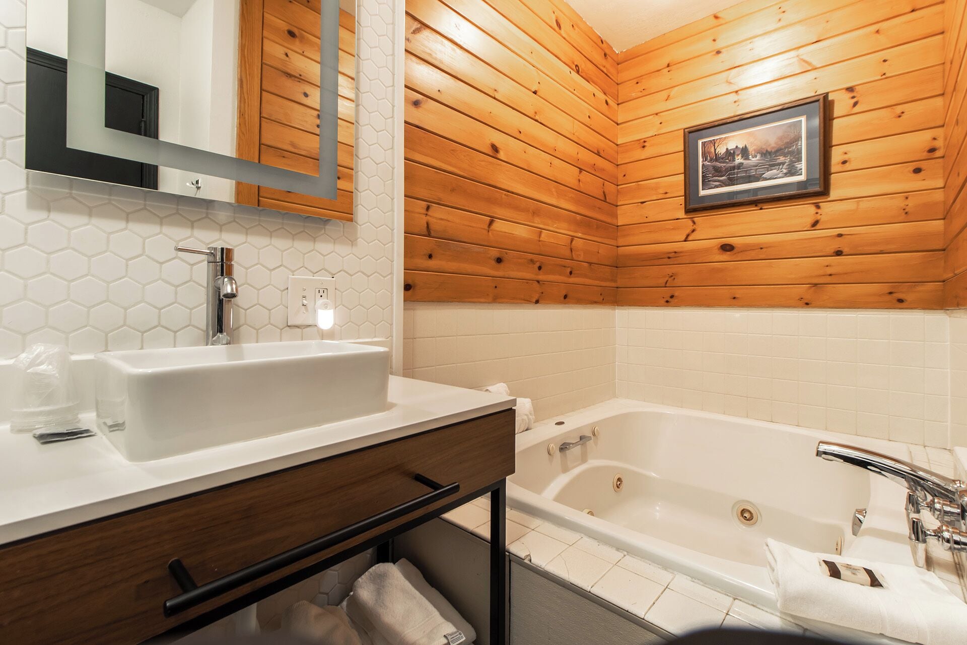 Un baño con paredes de madera, un lavamanos blanco, un espejo y una bañera.