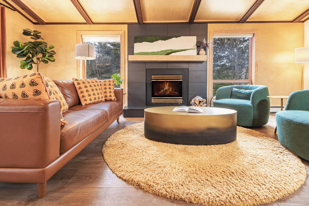 A modern living room with a leather sofa, a round coffee table, and a fireplace.