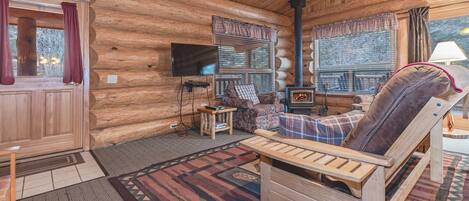 L’intérieur d’un chalet en bois chaleureux et accueillant, avec une cheminée, un téléviseur et un coin salon confortable.