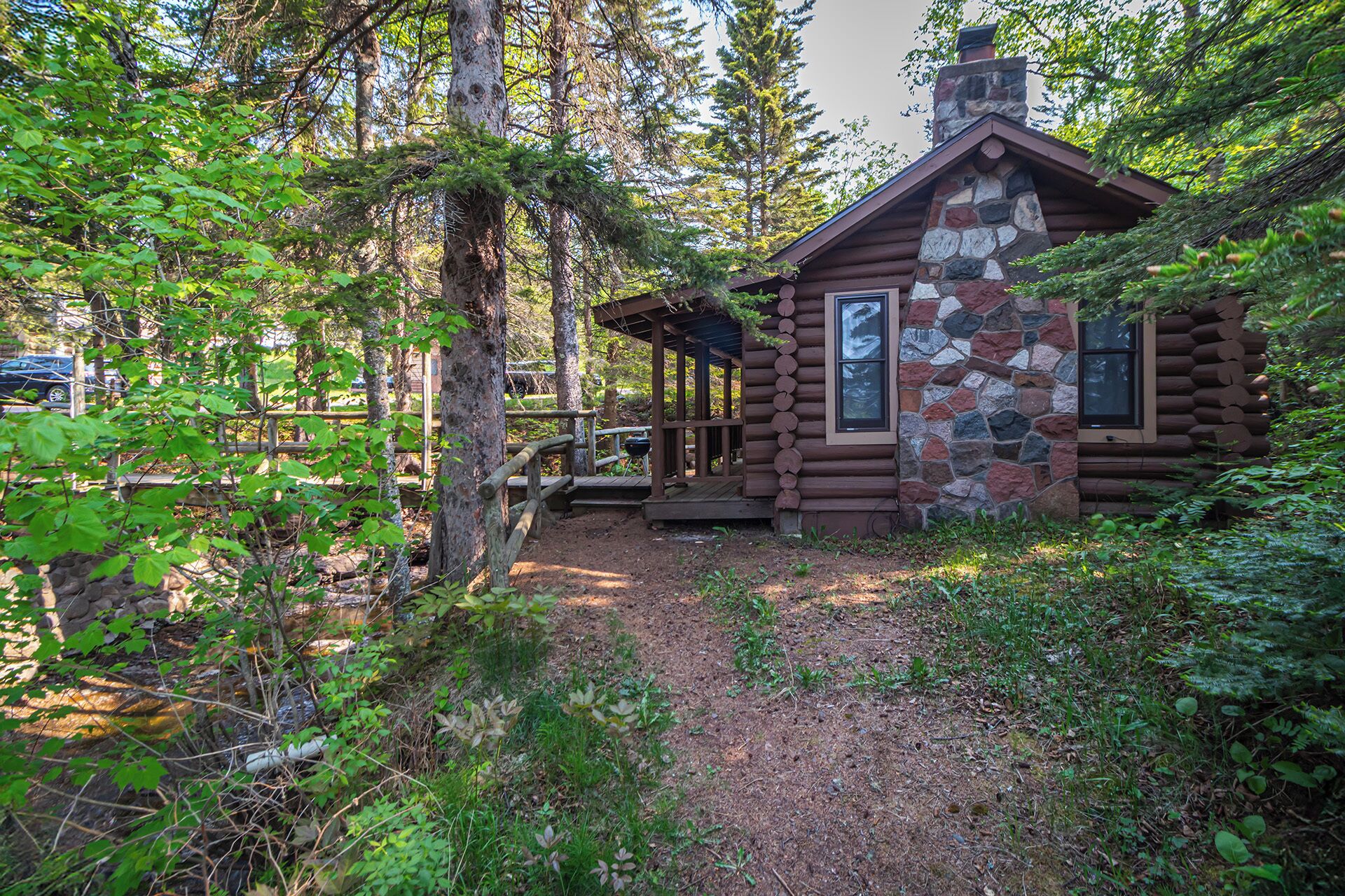 Un chalet rustique aux murs en pierre et en bois, entouré d’une forêt dense.