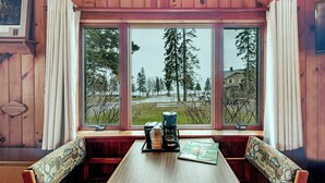 A wooden-paneled room with a large window, a table with a magazine, and a coffee maker. - Cascade Lodge (Lutsen)