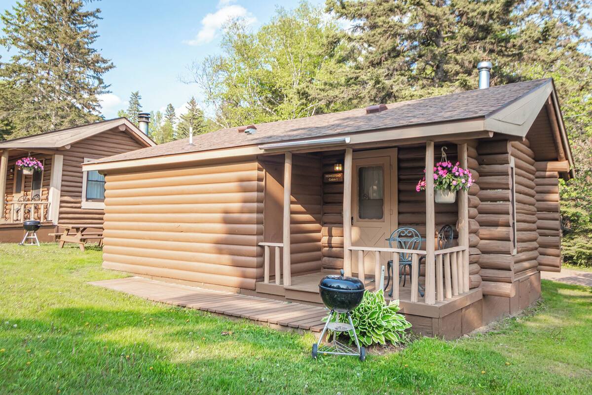 A log cabin with a porch, a grill, and a sign indicating a cabin number.