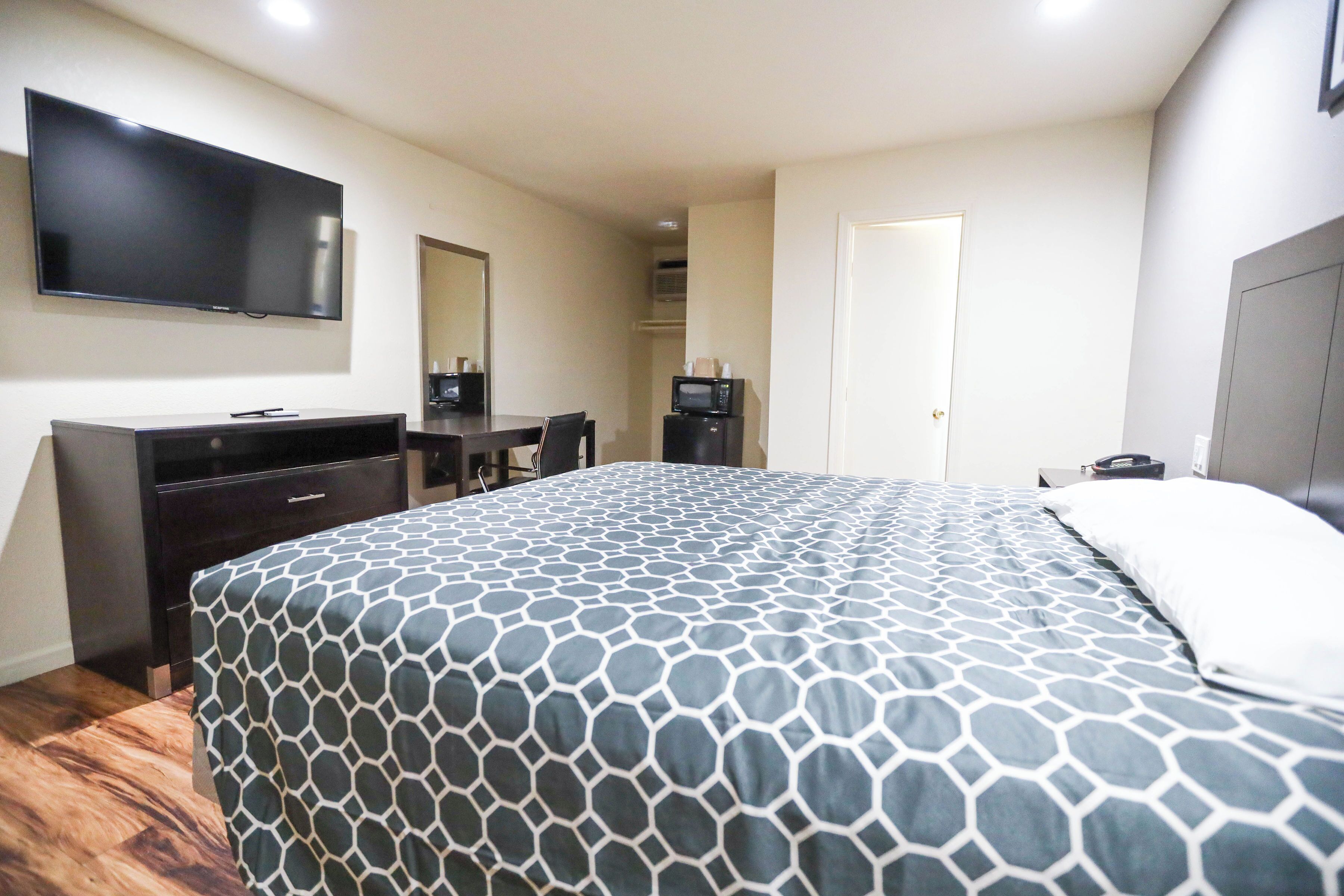 A hotel room with a bed, a TV, a desk, and a wardrobe.