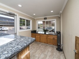 Una cocina con encimera de granito, armarios de madera y ventana con vista a un estacionamiento.