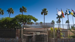 A gated entrance with palm trees and flags, indicating a resort or hotel setting. - Relaxia Los Girasoles (San Bartolomé de Tirajana)