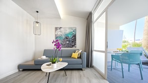 A modern living room with a grey sofa, a round coffee table, and a painting on the wall. - Relaxia Los Girasoles (San Bartolomé de Tirajana)