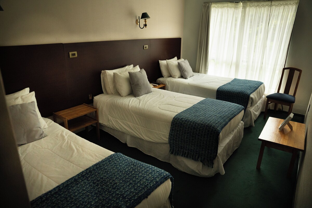 A hotel room with two beds, a desk, and a chair.